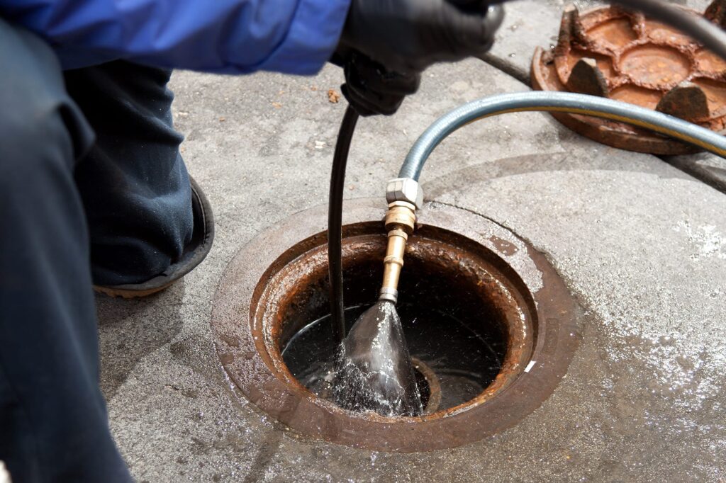 Plumber hydro jetting a sewer line through a manhole in Murrysville